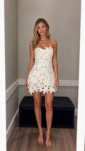 Model wearing white 3d floral strapless mini dress, front view