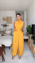 Front view of mustard halter neck wide leg jumpsuit with draped waist and pockets