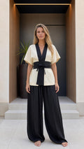 Front view of woman wearing beige kimono top and black wide-leg pants set