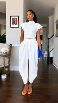 Front view of white mock neck cap sleeve harem jumpsuit with defined waist and tapered legs