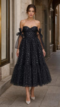 Front view of model wearing black starlight off-shoulder tulle midi dress