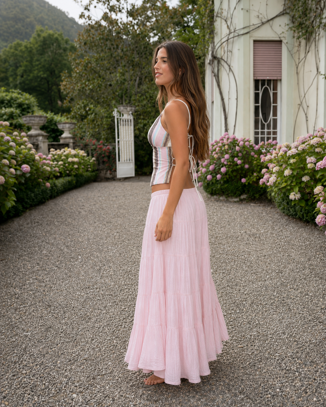 Side view of a women's striped corset cami top with blush pink tiered maxi skirt set
