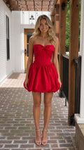 Front view of woman wearing red strapless bow mini dress