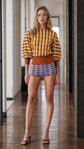 Front view of model wearing mustard striped knit sweater and patterned shorts set