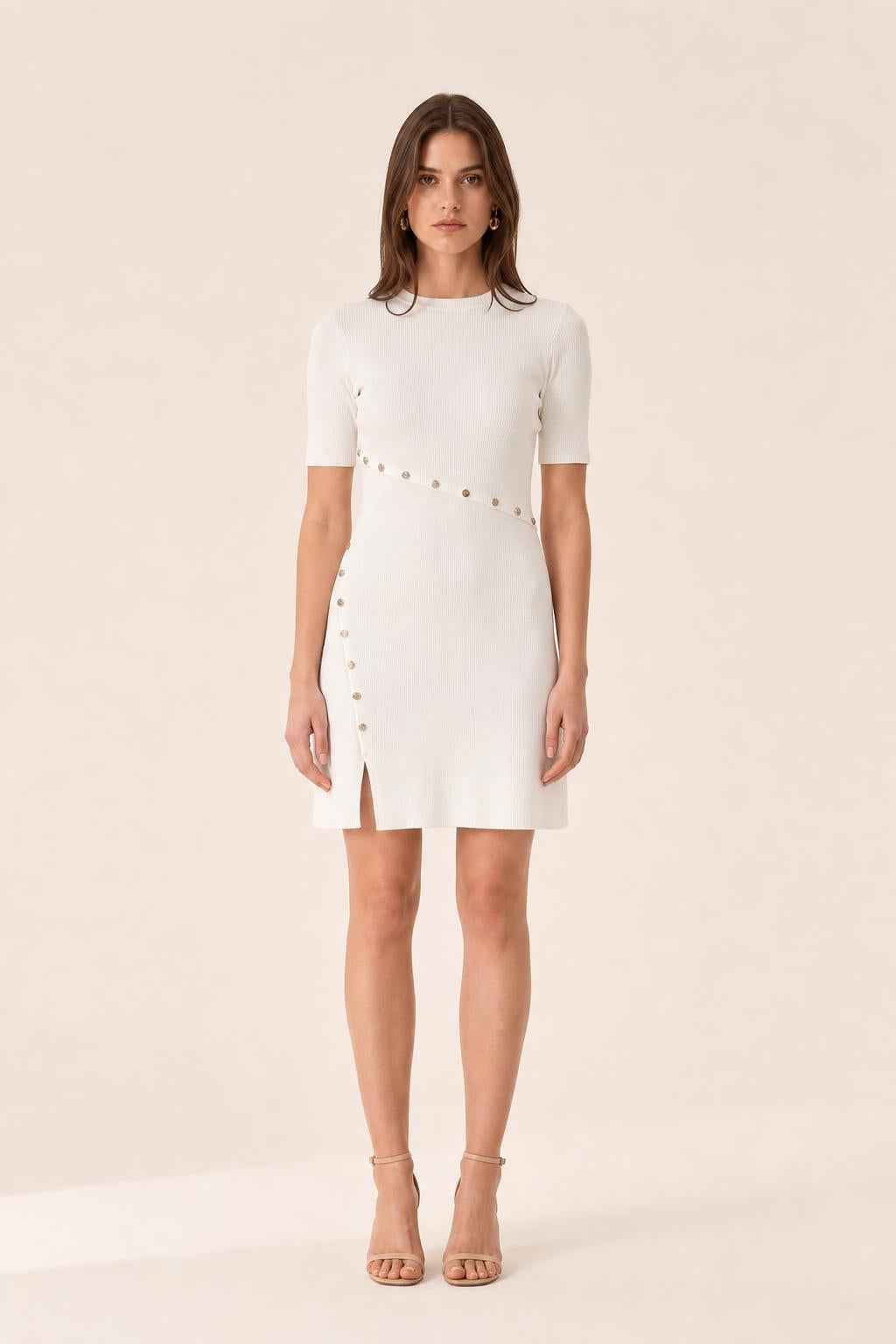 Front view of woman wearing white ribbed knit mini dress with gold buttons