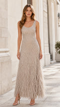 Front view of woman wearing champagne sequin evening gown with feather hem