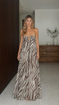 Front view of model wearing brown zebra print strapless maxi dress