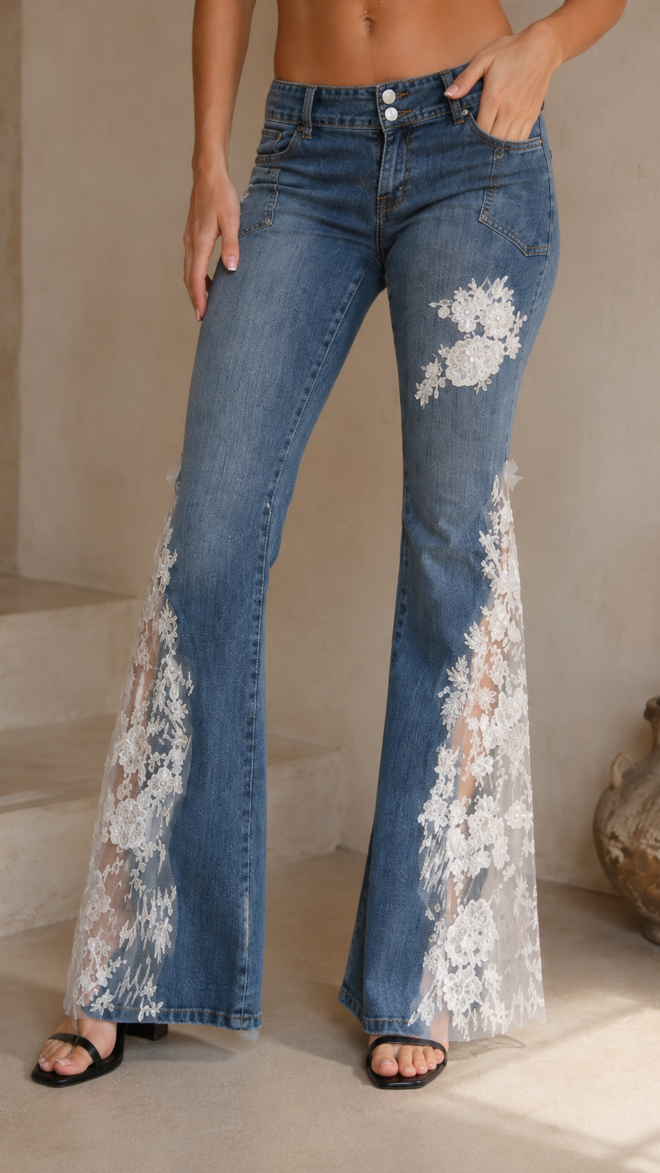 Close front detail of medium wash blue flare jeans with floral lace panel accents