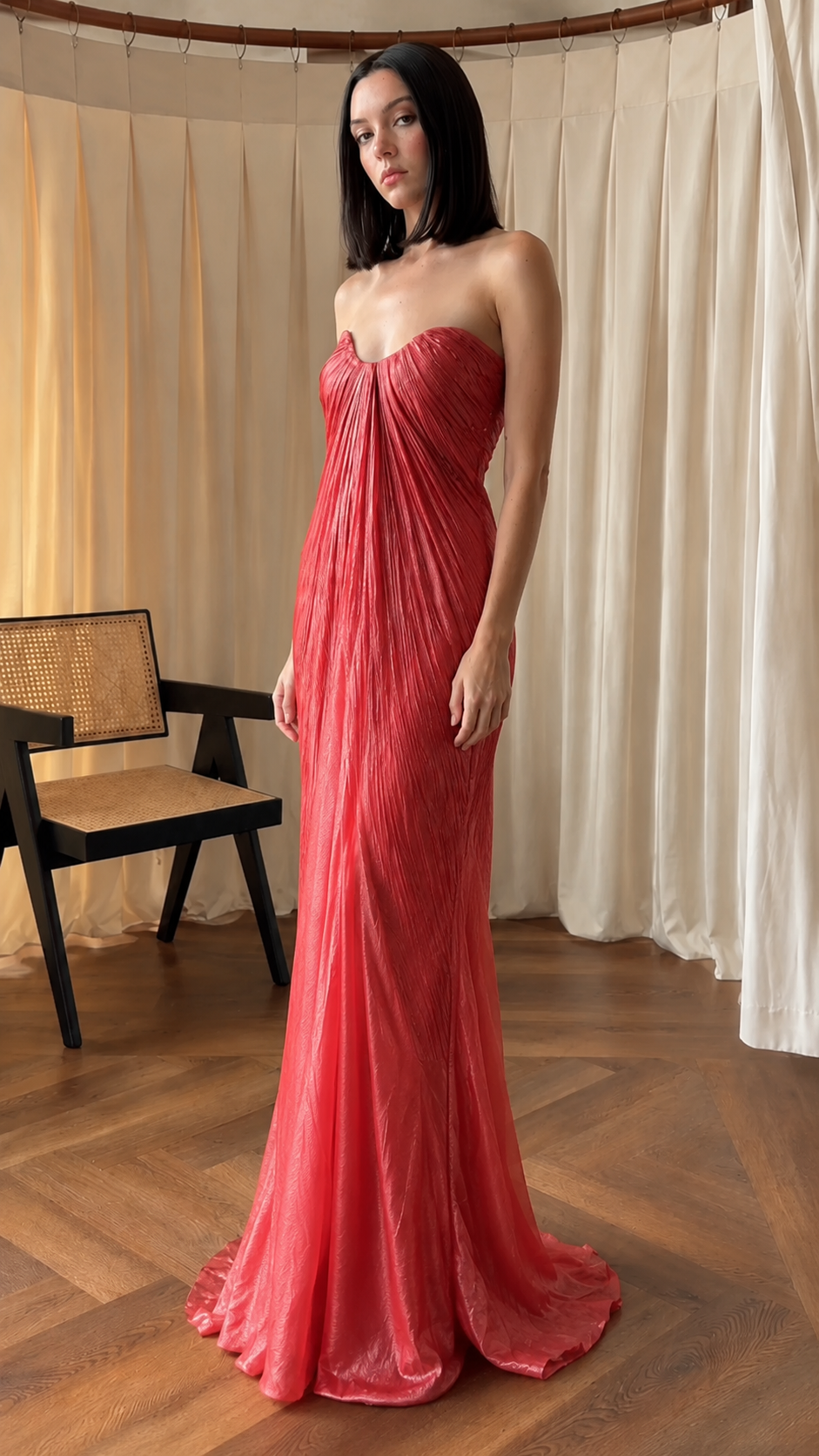 Angled front view of rose red strapless pleated floor-length gown
