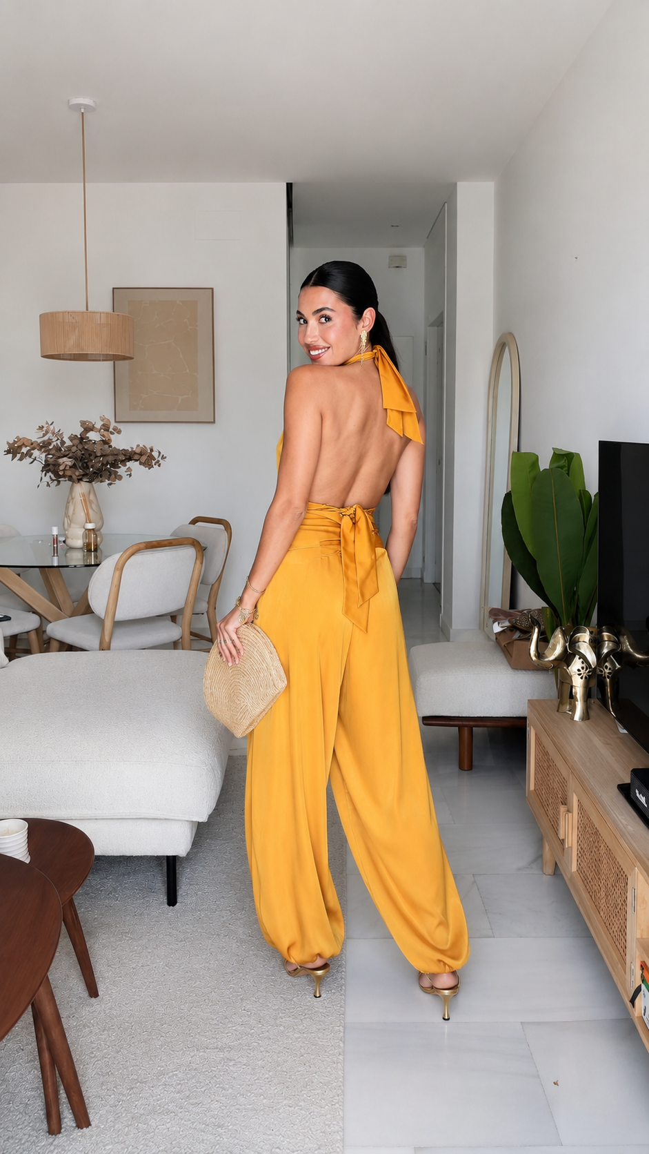 Back view of mustard backless halter jumpsuit with tie closure and flowing legs