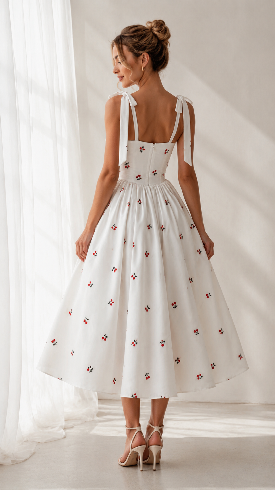 Back view of white cherry print midi dress with tied shoulder straps and gathered skirt