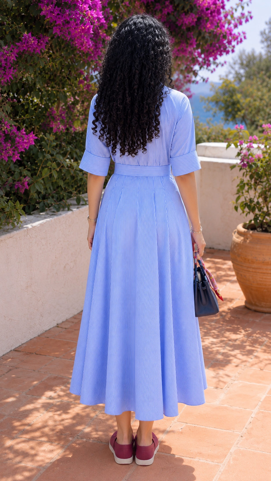 Back view of sky blue striped belted shirt maxi dress with flowing pleated skirt