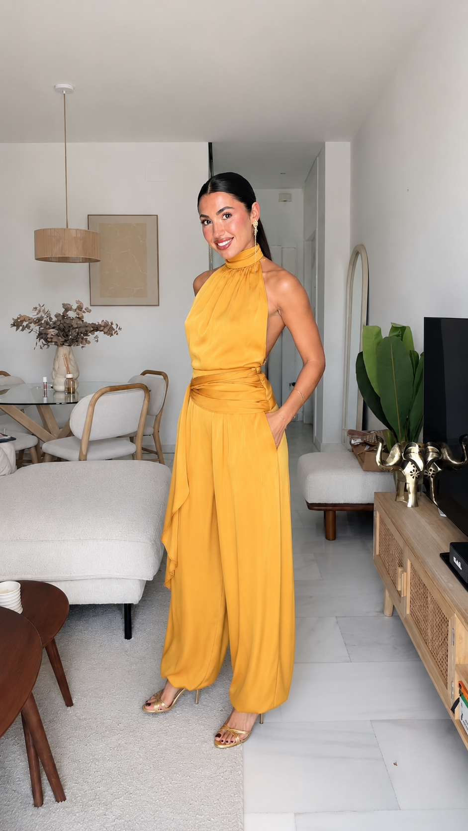 Angled front view of mustard halter jumpsuit with wide legs and side pockets