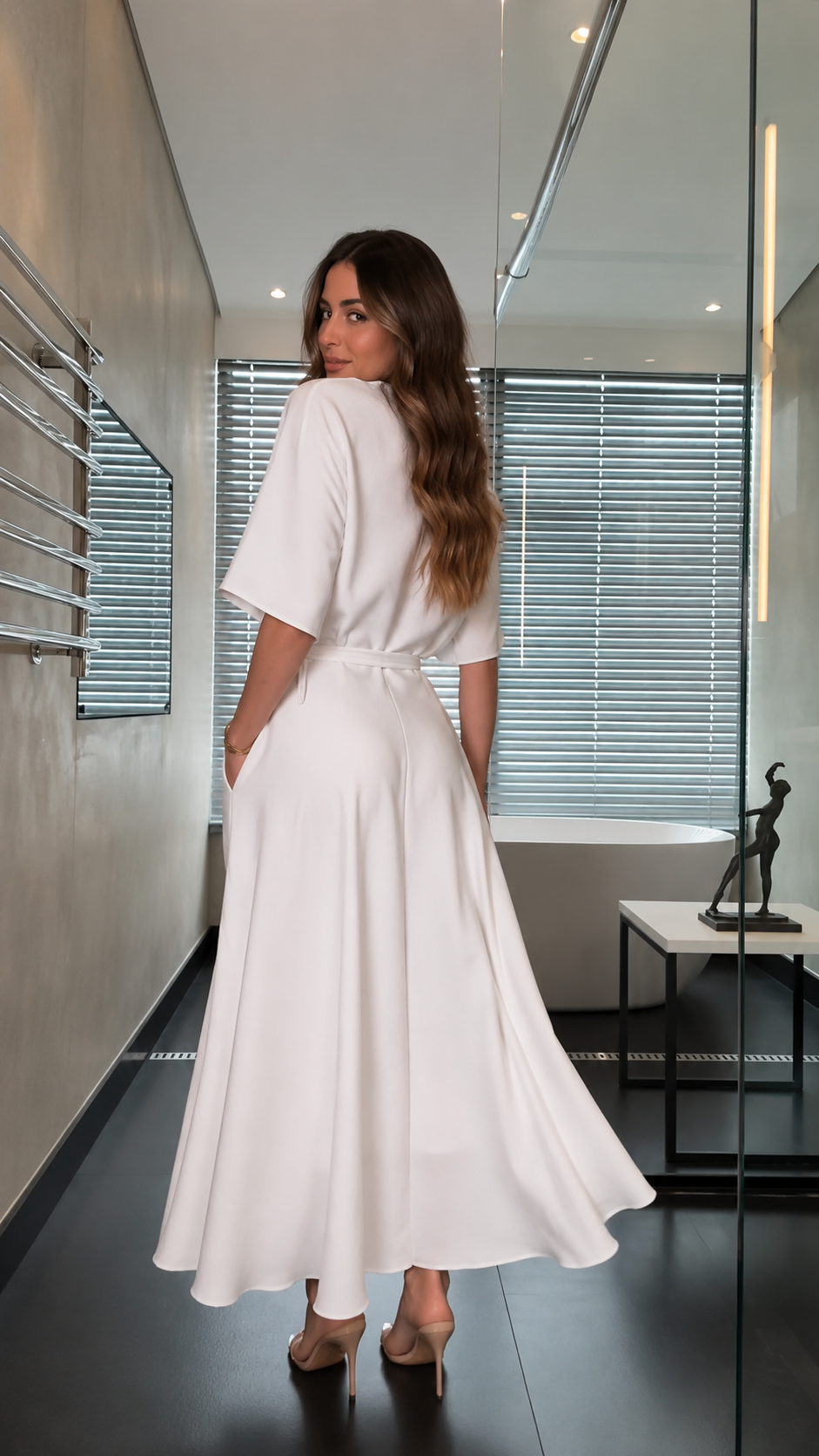 Back view of white A-line dress showing flowing skirt and waist tie detail