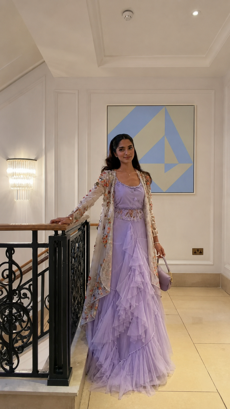 Woman wearing a lavender tiered gown with a square neckline and embroidered cape overlay