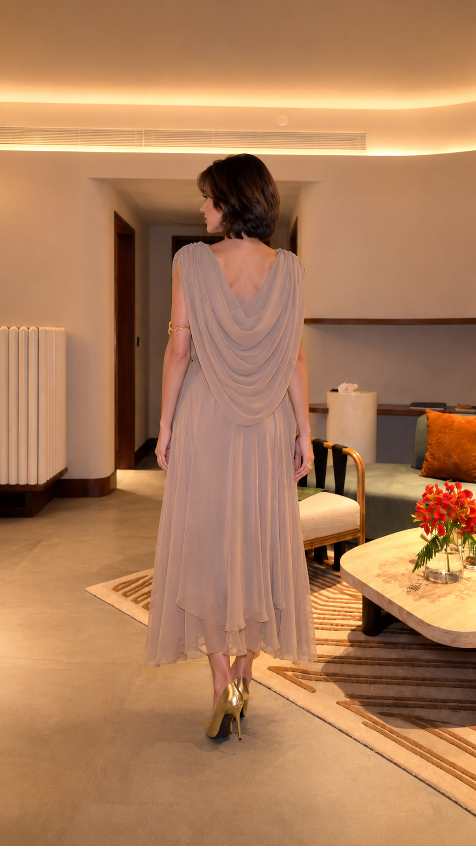 Back view of taupe draped midi dress showing flowing overlay and layered hem