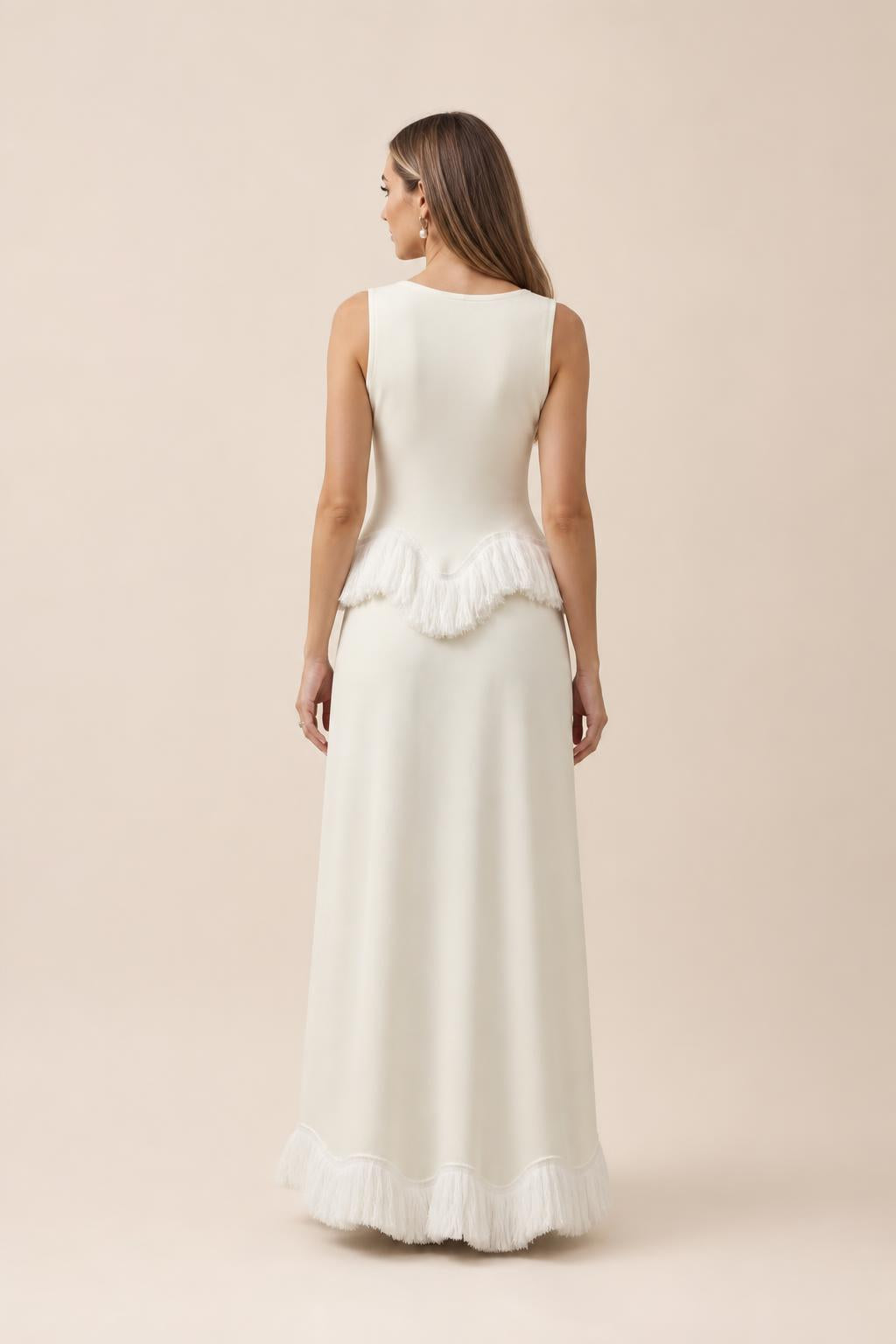 Back view of white fringed peplum maxi dress against neutral studio backdrop
