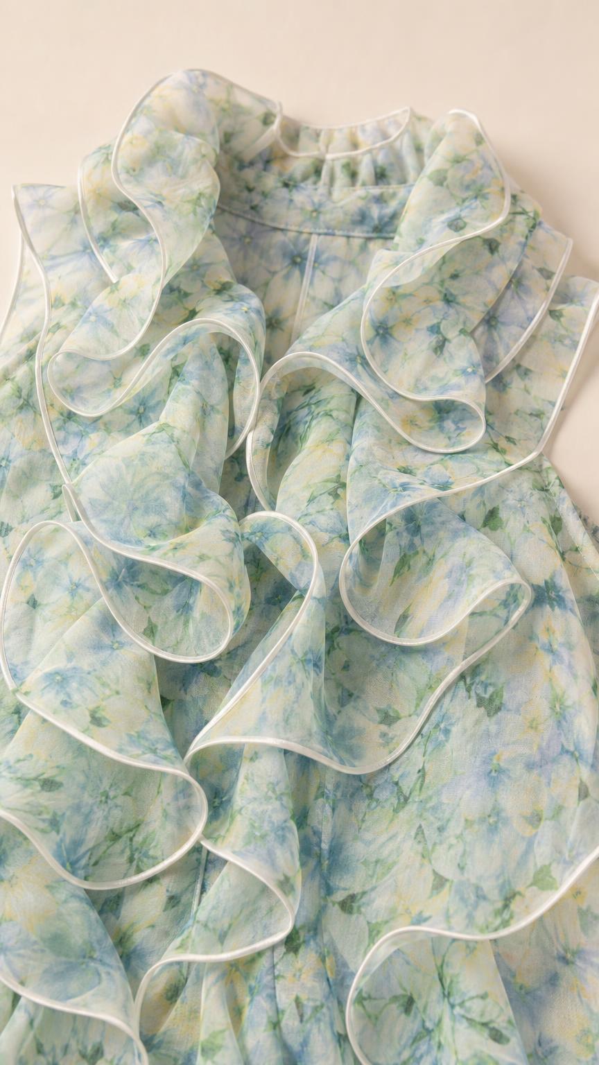 Close-up detail of light blue floral fabric and ruffled neckline