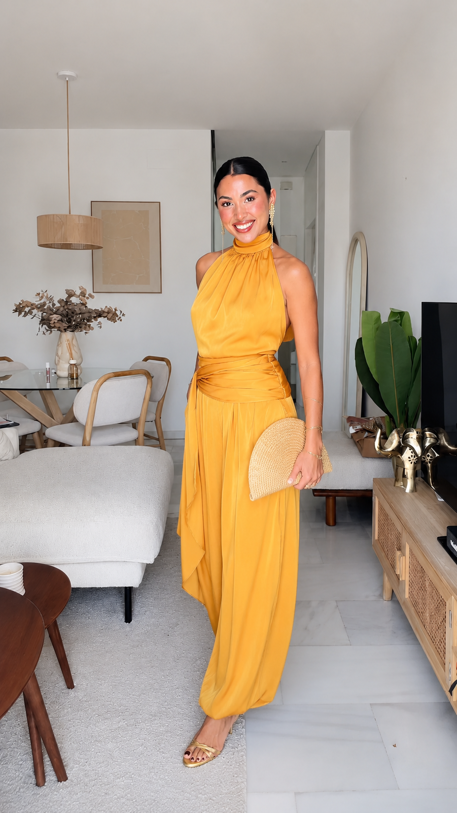 Mustard halter wide leg jumpsuit styled with a woven clutch