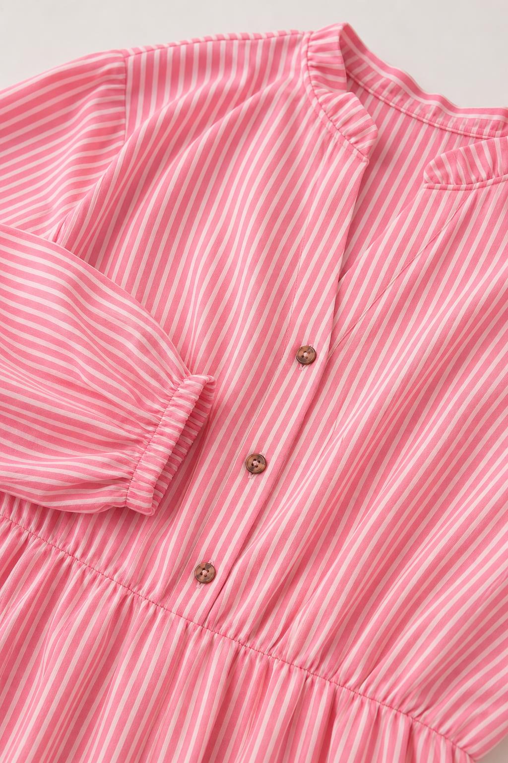 Close-up detail of buttons, collar, and fabric texture on pink striped dress