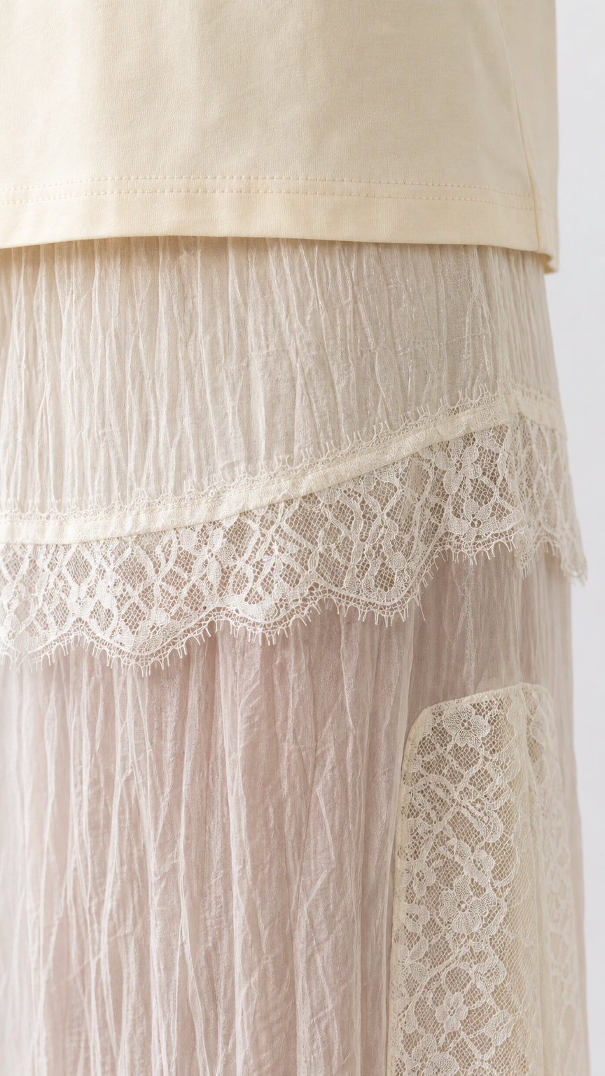 Close-up detail of lace trim and crinkled texture on cream skirt