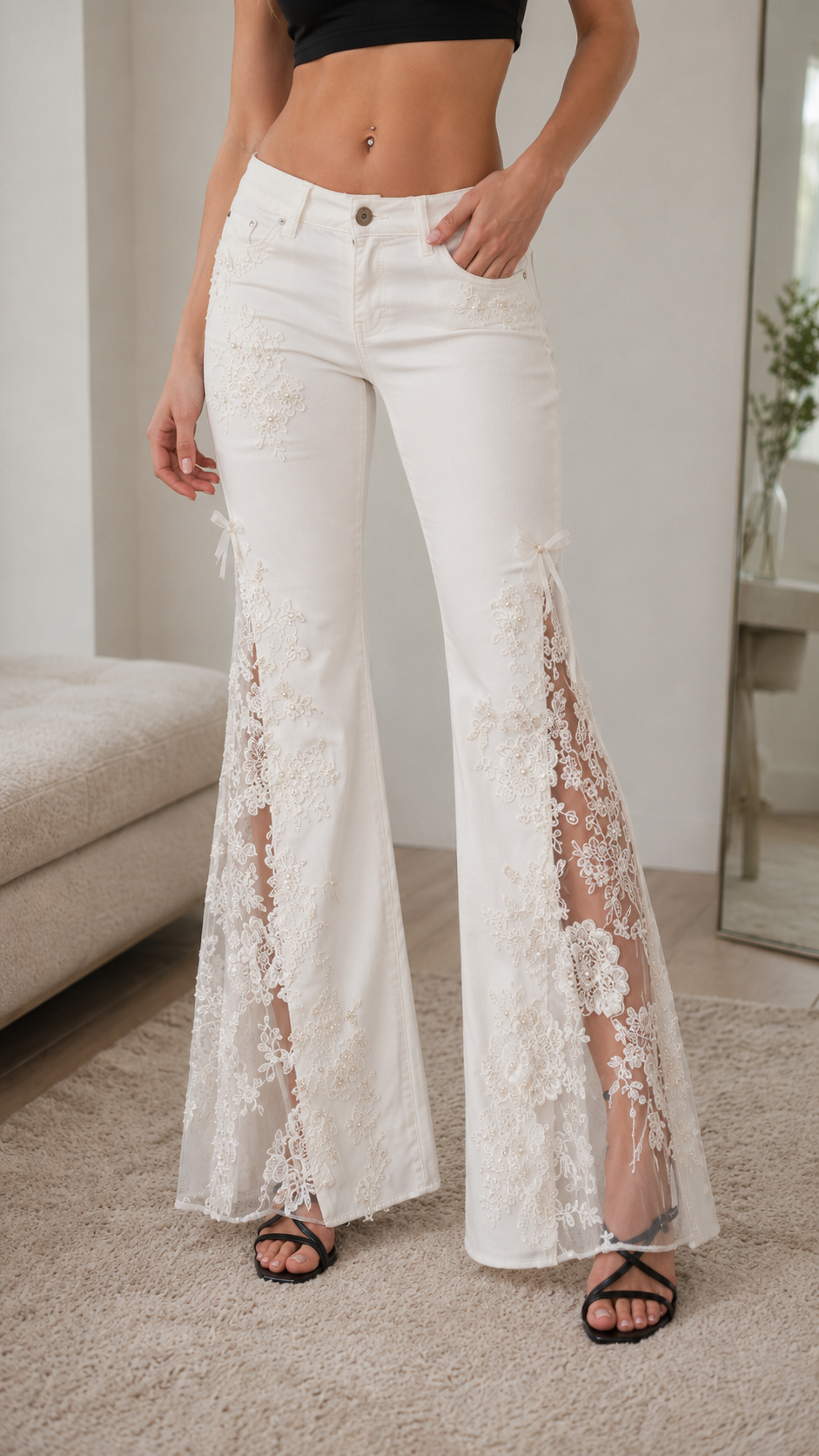 Close-up front detail of white pants with floral lace inserts and flare hem