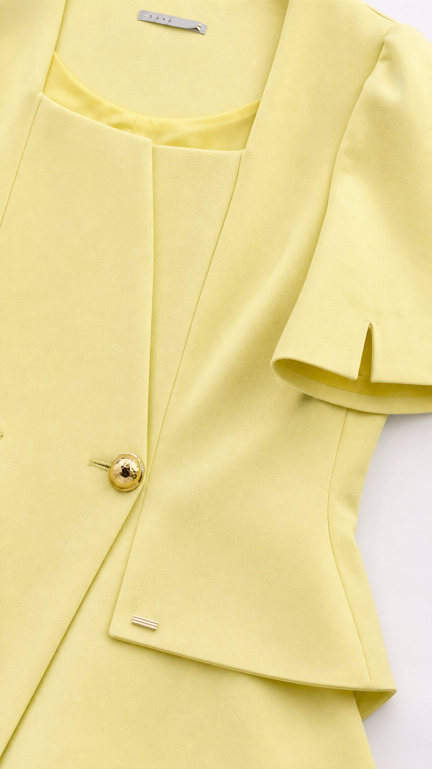 Close-up detail of yellow jacket neckline and gold buttons