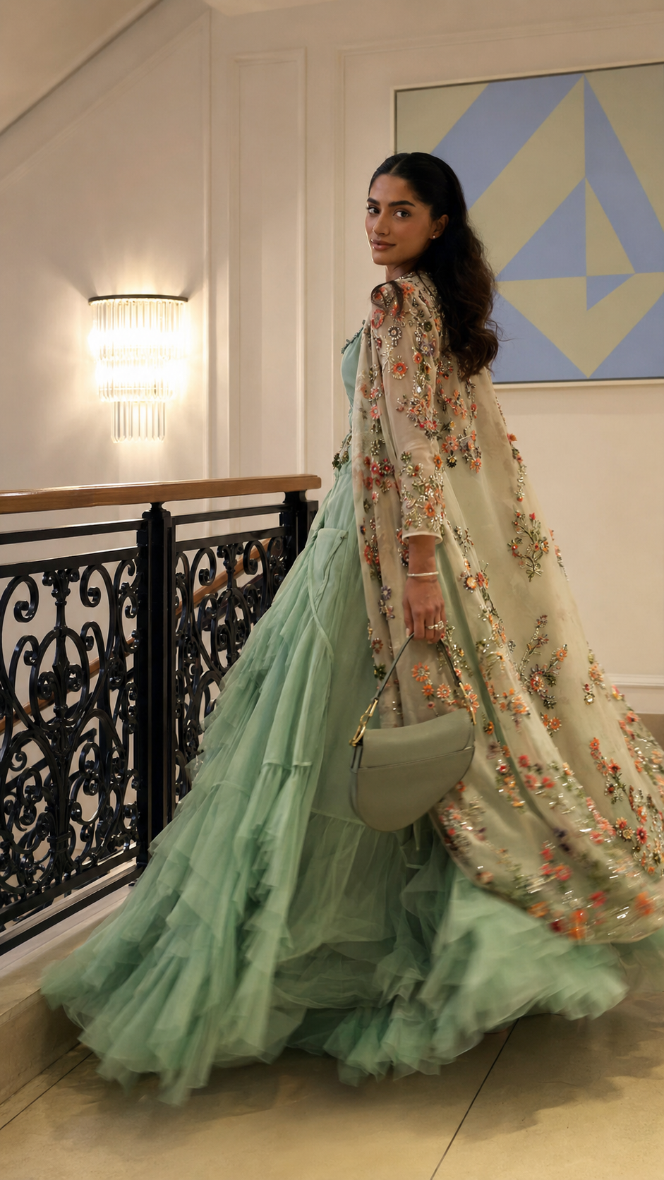 Side view of the mint green gown showing the flowing layered skirt and embroidered cape