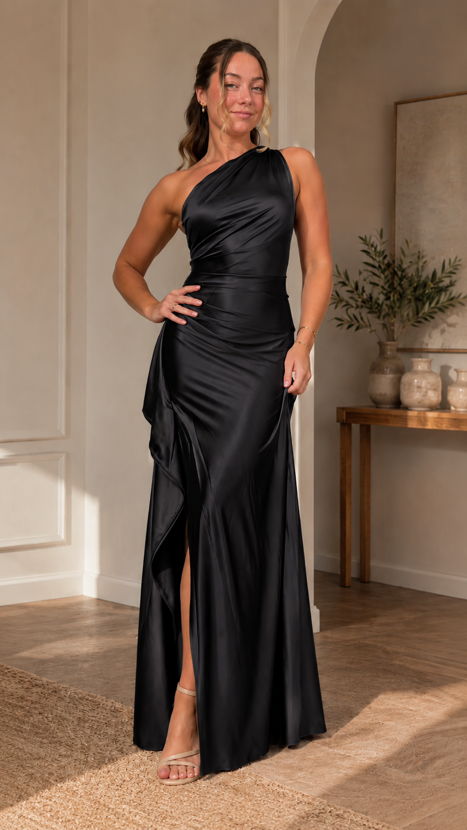 Front view of black one-shoulder satin-like maxi dress with side ruffle and slit