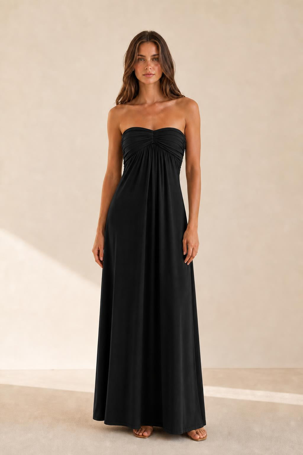 Woman wearing black strapless ruched maxi dress front view