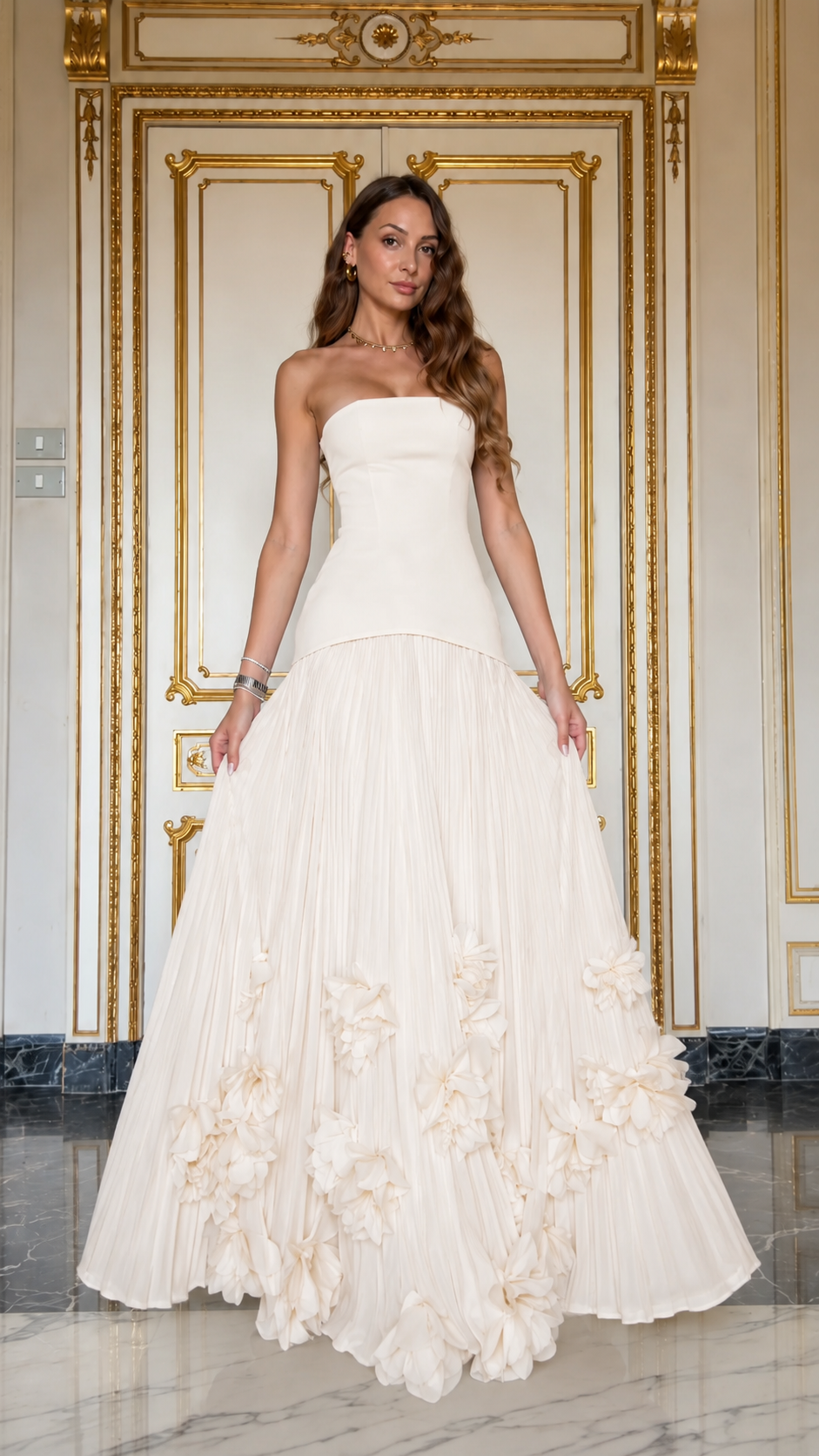 Front view of ivory strapless pleated maxi gown with textured floral hem