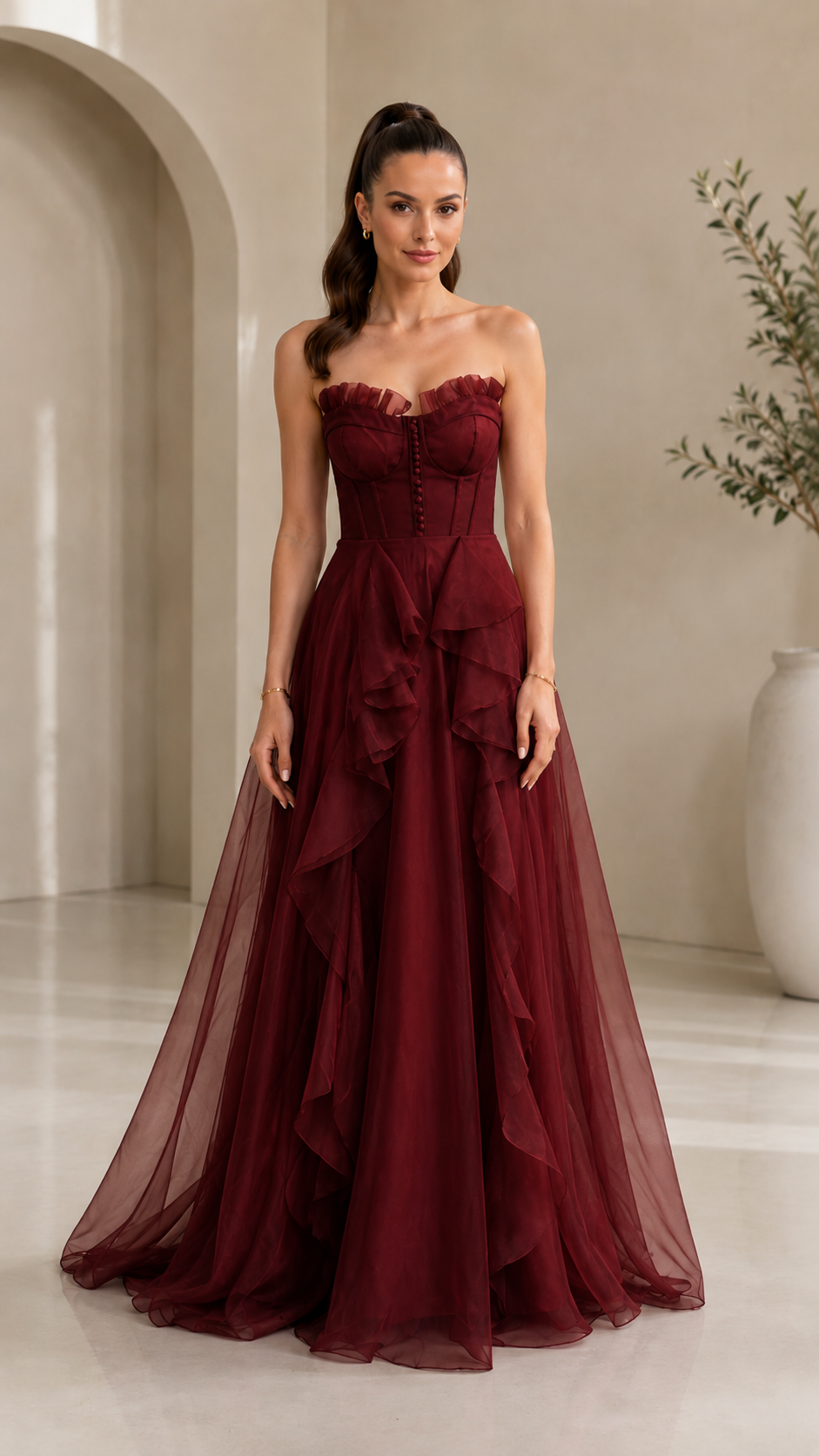 Front view of burgundy strapless corset gown with flowing ruffle detail