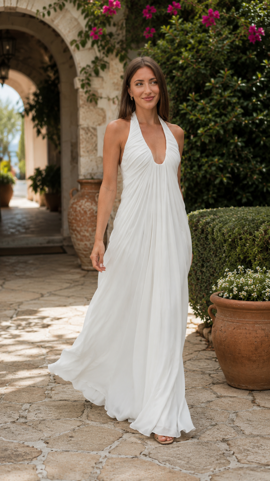 White pleated halter maxi dress shown walking with flowing hem