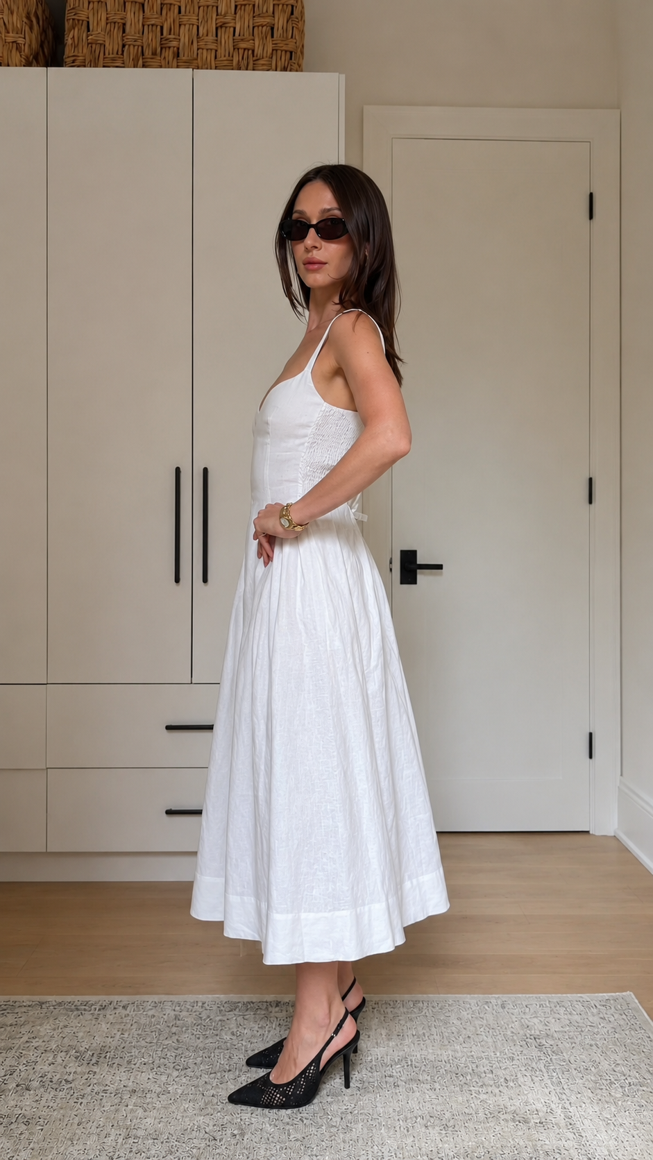 Side view of a white sleeveless sweetheart neck midi dress with structured bodice seams