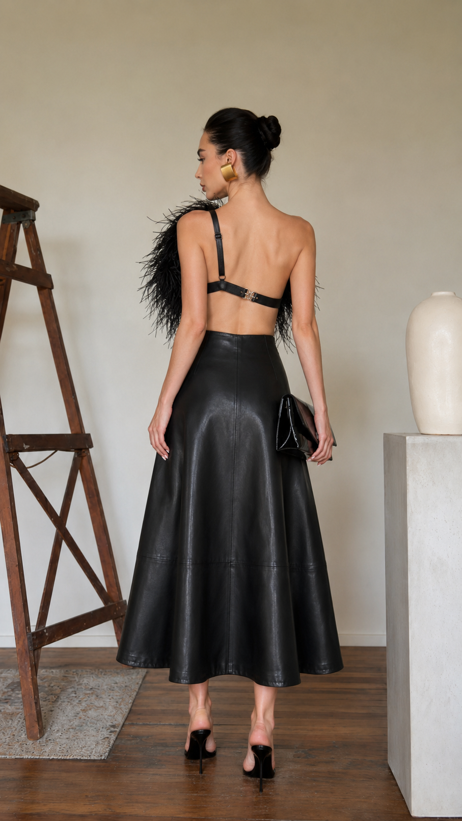 Back view of the black faux leather A-line midi skirt showing the flared silhouette and midi length