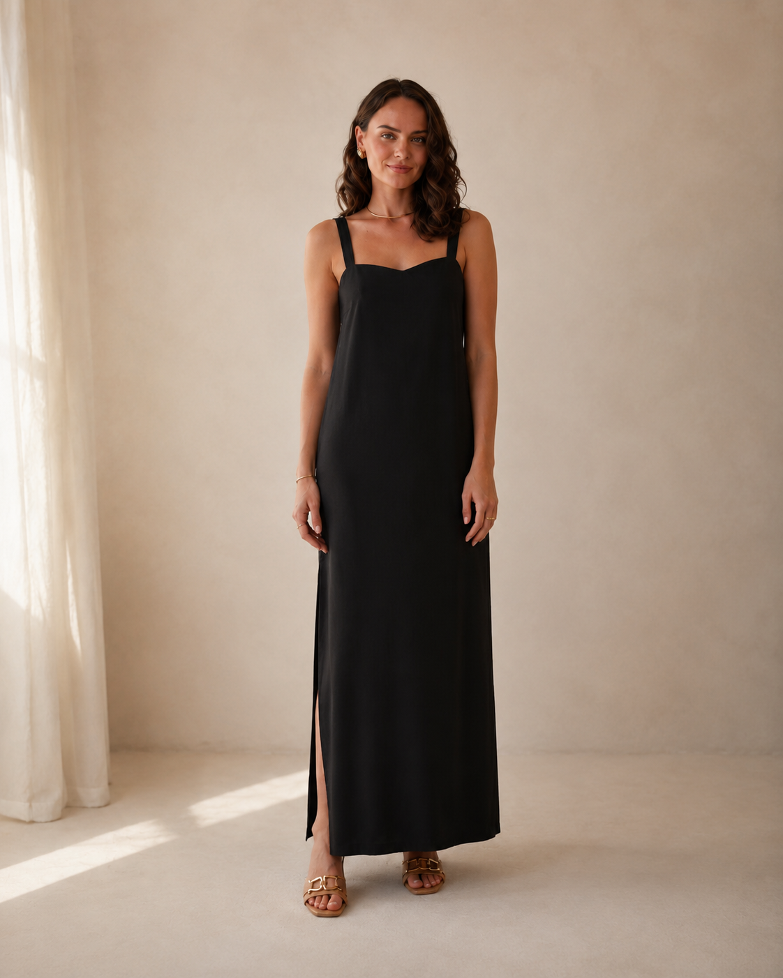 Front view of black sleeveless square neck maxi slip dress with side slit