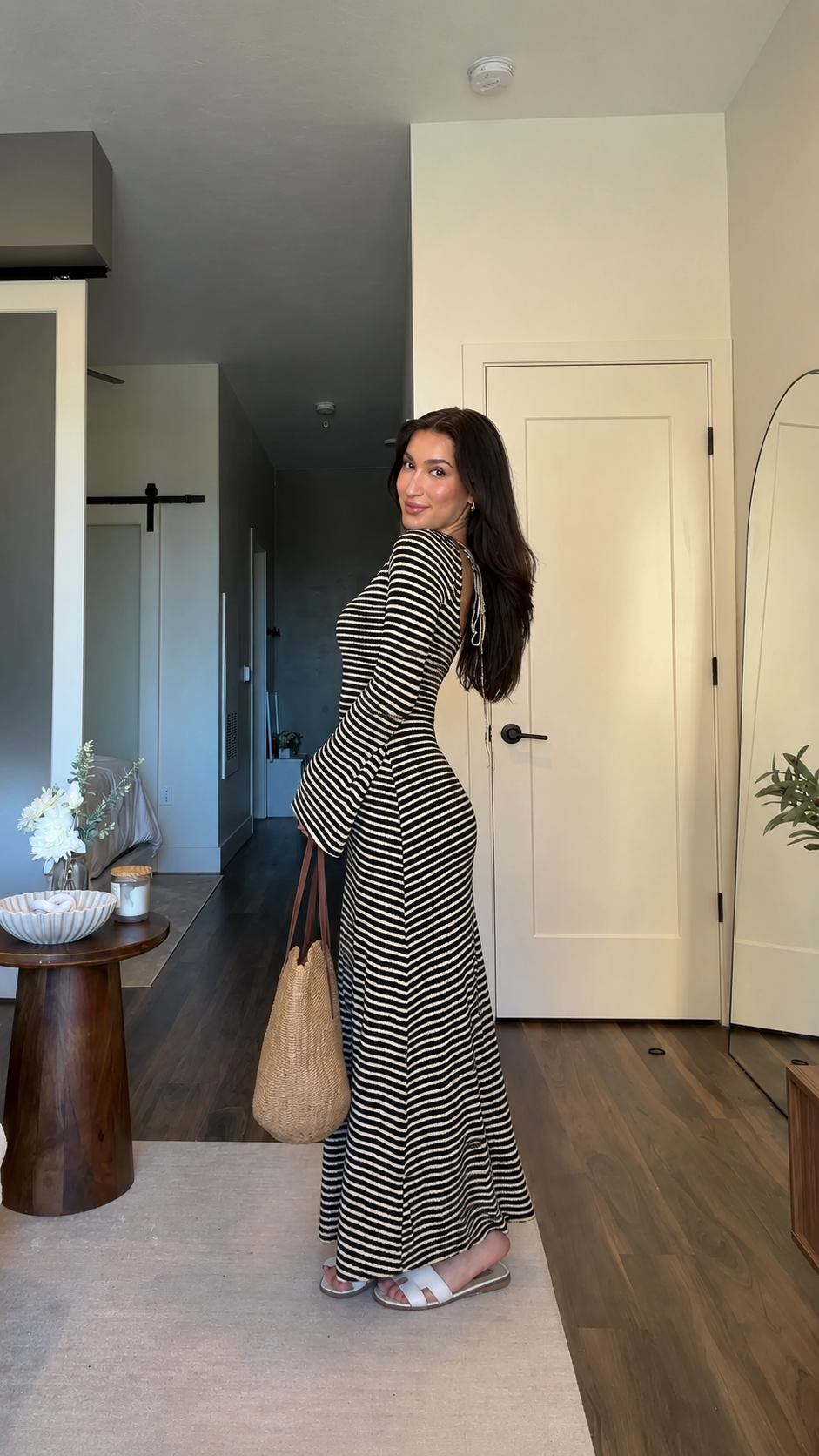 Side-back view of black striped maxi dress with open back and flared hem